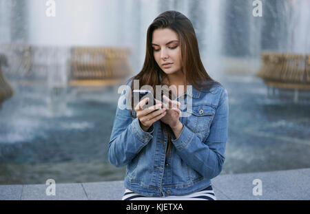 Caucasian woman texting on cell phone at Fountain Banque D'Images