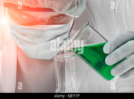 Caucasian scientist pouring liquid into beaker vert Banque D'Images