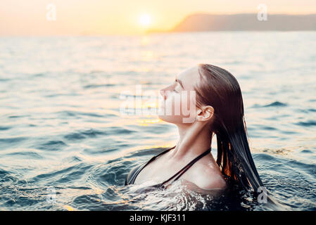 Caucasian woman piscine au coucher du soleil Banque D'Images