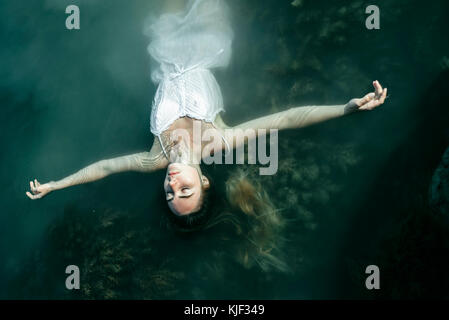 Caucasian woman wearing dress floating in water Banque D'Images