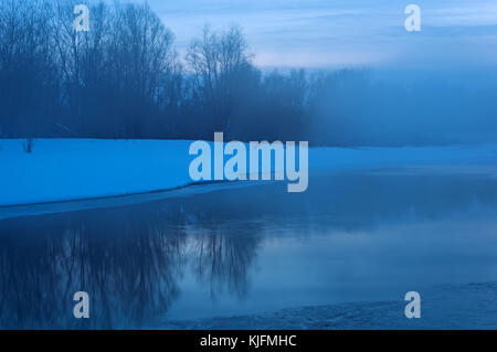 Nuit paysage avec la rivière, partiellement recouvert de glace, neige sur la rive et la brume sur l'eau, l'exposition à long shot Banque D'Images