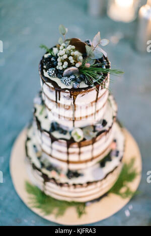 La cuisine, confiserie, fait main concept. close up de traiter pour mariage, richement décoré gâteau avec glaçage foncé, doux et mûres, mis sur big flat plaque blanche Banque D'Images