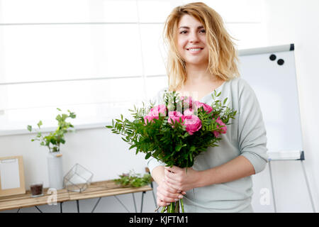 Photo de femme composition fleuriste bouquet près de table en bois, dans l'après-midi prix Banque D'Images