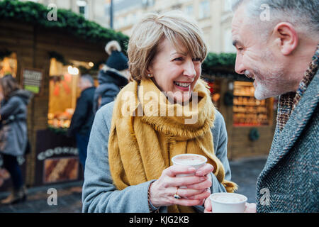 D'âge mûr sont bénéficiant d'une tasse de café dans leur exploration de la ville Marché de Noël. Banque D'Images