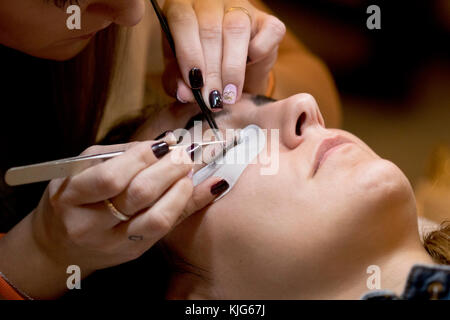 Gros plan image d'un professionnel ajoutant des extensions de cils à un client dans salon look Madrid 2017. Banque D'Images