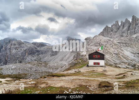 Petite vieille cabane sur le bord du mont paterno à côté dreizinnen hut avec drapeau italien à l'avant, Dolomites, Italie Banque D'Images