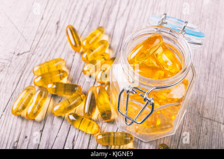 Close up of omega-3 fish oil capsules fat sur planche de bois dans un pot Banque D'Images