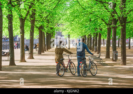 Les jeunes de Berlin, vue sur un après-midi de printemps tardif d'un jeune couple poussant leurs vélos dans le parc Lustgarten de Berlin, Allemagne. Banque D'Images