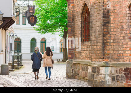 La marche mère-fille, une jeune femme met sa main sur l'épaule de sa mère comme ils se promener ensemble au quartier Nikolaiviertel à Berlin, Allemagne Banque D'Images