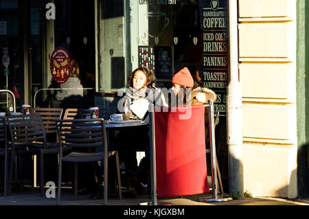 Tayside, Dundee, Ecosse, Royaume-Uni. 23 novembre, 2017. Deux étudiantes de l'Asie de l'enveloppé du froid chaud assis dehors café Costa jouissant de leurs rafraîchissements dans le centre-ville de Dundee. Crédits : Dundee Photographics/Alamy Live News Banque D'Images