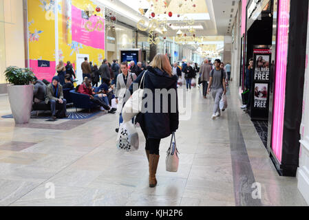 Femme portant des sacs de shopping le Black Friday après une frénésie de dépenses dans un centre commercial, au Royaume-Uni Banque D'Images