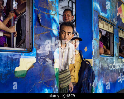 Yangon, région de Yangon, Myanmar. 25 novembre 2017. Passagers debout devant la porte d'un train circulaire de Yangon arrivant à la gare centrale de Yangon. Le Yangon Circular train est un système de boucle à deux voies de 45 kilomètres (28,5 mi) de 39 stations qui relie les villes satellites et les banlieues au centre-ville. Le train a été construit pendant la période coloniale britannique, la deuxième voie a été construite en 1954. Les trains circulent actuellement dans les deux sens (sens horaire et sens antihoraire) autour de la ville. Les trains sont le moyen le moins cher de traverser Yangon et ils sont très populaires auprès de la classe ouvrière de Yangon. Environ 10 Banque D'Images