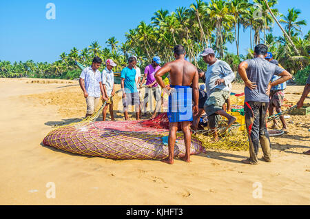 Bentota, Sri Lanka - 6 décembre 2016 : l'équipage de pêche se trouve à côté de la seine, plein de friture de poissons, et se prépare à partir de boîtes pour transpo Banque D'Images