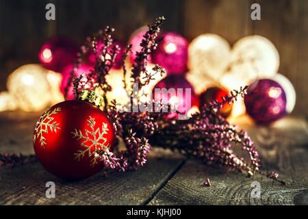 Boule de Noël rouge et rose heather séché sur planche de bois rustique. bokeh doux lumières dans l'arrière-plan. Ce peut être utilisé comme Noël ou Nouvel an g Banque D'Images