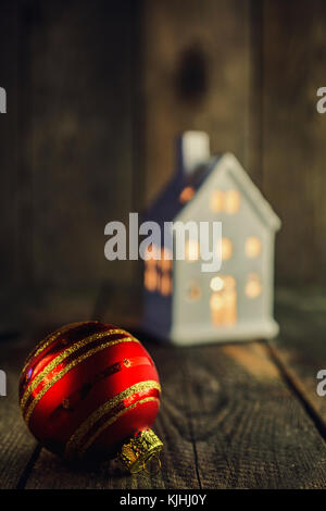 Boule de Noël et en forme de maison blanc bougeoir céramique sur fond de bois rustique. Ce peut être utilisé comme Noël ou Nouvel an carte de vœux. Banque D'Images