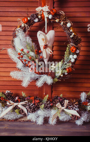 Couronne de Noël sur le mur en bois. éléments rouge et blanc, coeur textile se bloque Banque D'Images