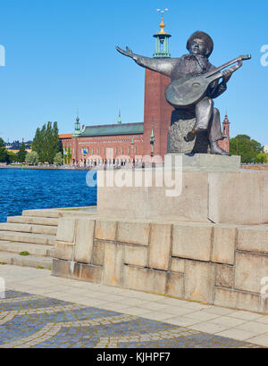 Statue de Evert Taube troubadour avant tout de la tradition suédoise ballade avec l'Hôtel de Ville (Stadshuset) en arrière-plan, Riddarholmen, Stockholm, Suède Banque D'Images