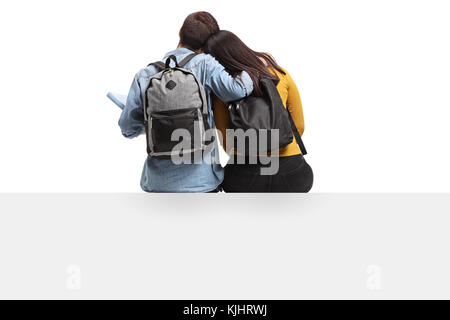 Vue arrière tourné d'étudiants adolescents dans une étreinte assis sur un panneau isolé sur fond blanc Banque D'Images