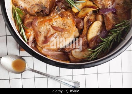 Close-up d'une cocotte de porc avec l'oignon, pomme et romarin Banque D'Images