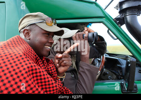 Guide Masai recherche jeu à travers les jumelles. Le Masai Mara. Au Kenya. Banque D'Images