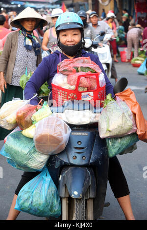 Femme sur un scooter à l'achat d'aliments au marché. Hoi An. Le Vietnam. Banque D'Images