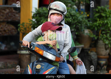 Femme avec fils la conduite d'un scooter. Hoi An. Le Vietnam. Banque D'Images