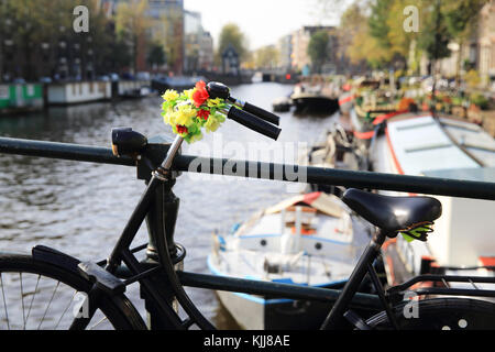 Des fleurs sur un vélo sur le Oude Schans canal, à l'automne le soleil, à Amsterdam, aux Pays-Bas, en Europe du nord Banque D'Images