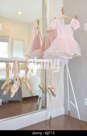 Girl's robe rose et chaussures de ballet accrocher au bar dans la chambre Banque D'Images