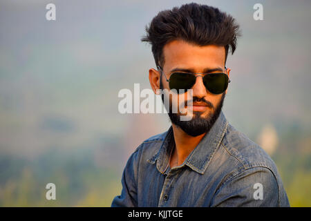 Jeune Indien avec des lunettes de soleil près de mountain, Pune, Maharashtra. Banque D'Images