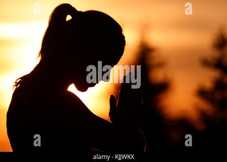 Silhouette d'une femme pratiquant le yoga contre la lumière de la soleil du soir. Alpes françaises. La France. Banque D'Images