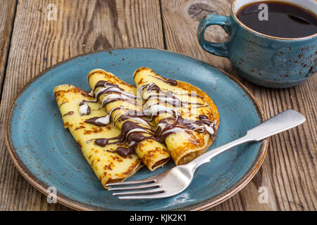 Crêpes farcies avec une sauce au chocolat, pour le petit-déjeuner sur la table en bois. studio photo Banque D'Images