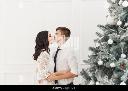 Couple d'adolescents à Noël. Ils ont l'air dans les yeux de chacun et baiser. un baiser sous le gui date pour les vacances. Banque D'Images