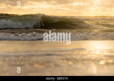 Vue de dessous sur les ondes de tempête sur une plage de sable fin avec un ciel nuageux Ciel de coucher du soleil Banque D'Images