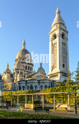 Les trois-quarts arrière vue sur la Basilique du Sacré-Cœur de Paris au lever du soleil en automne vu à partir d'un jardin public avec des bancs et une pergola. Banque D'Images