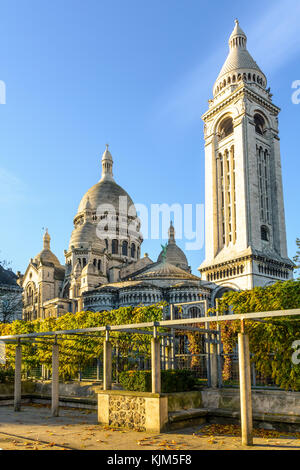 Les trois-quarts vue arrière de la Basilique du Sacré Coeur de Paris au lever du soleil en automne vu à partir d'un jardin public avec une pergola à l'avant-plan. Banque D'Images