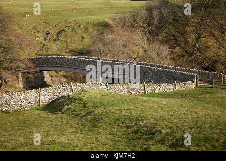 En après-midi, soleil d'automne une dalle de pierre avec parapets de pont enjambe la rivière Lowther à Shap Shap, abbaye, Cumbria Banque D'Images