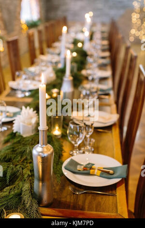 Décoration de mariage, de l'intérieur, de concept d'éclairage. close up de table des fêtes servi avec des bougies dans des porte-originaux qui ressemble à bouteilles, parmi eux il y a des branches de conifères Banque D'Images