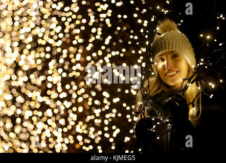 Dannielle McAllister regarde à travers une haie de hêtres couverte de lumières de fées qui fait partie d'une série d'installations lumineuses qui se trouvent à Noël au Botanics qui est un sentier illuminé d'un kilomètre à travers le jardin botanique royal d'Édimbourg. Banque D'Images