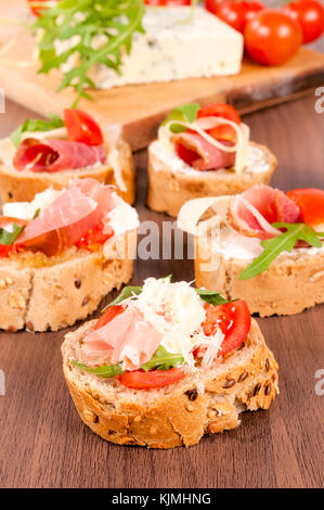 Des antipasti italiens bruschetta croustillant appelé surmontée de tomate, ail et basilic sur planche de bois (selective focus, focus sur la tomate p Banque D'Images