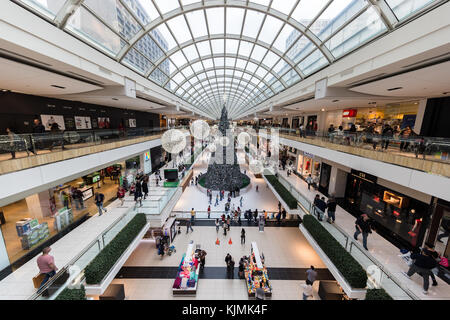 Gens occupés à vacances de Noël shopping dans le centre commercial Galleria Mall, le sapin de noël géant et patinage rink visible dans la distance Banque D'Images