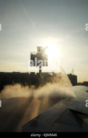 Un homme debout sur une plate forme élévatrice, la pulvérisation du liquide de dégivrage sur une aile d'avion tôt le matin avant l'avion peut décoller. L'hiver. Banque D'Images