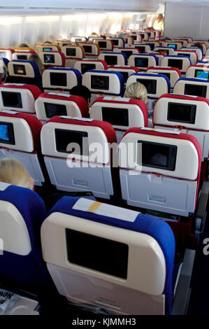 Les passagers assis dans la cabine de classe économique avec le siège en arrière des écrans vidéo LGW-ANU Banque D'Images