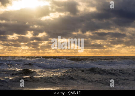 Le soleil et les rayons du soleil font leur chemin à travers les nuages de la mer agitée Banque D'Images