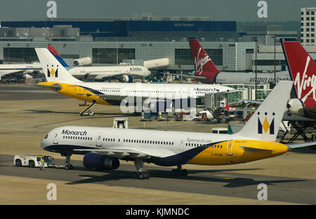 Un monarque Boeing 757-200 remorqué par un remorqueur par un Airbus A300, deux 747-400 Virgin Atlantic et Delta Air Lines 767-300 stationné à la gare et de Banque D'Images