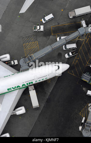 Un Boeing 747-400 d'Air EVA garé au terminal avec passerelle étendu, les bagages et les camions sur l'aire de restauration Banque D'Images