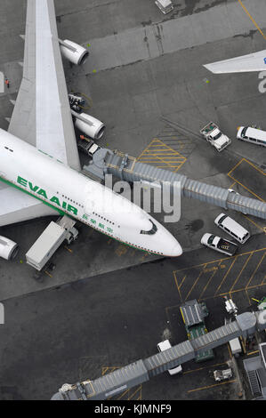 Un Boeing 747-400 d'Air EVA garé au terminal avec passerelle étendu, les bagages et les camions sur l'aire de restauration Banque D'Images