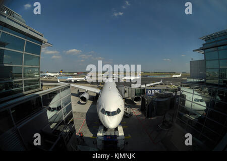 Lufthansa Airbus A330-300 garé au terminal avec Boeing 747-400 s, une 737 remorqué par un remorqueur, LOT Polish Airlines et Aegean 737 Embraer 170 taxi Banque D'Images