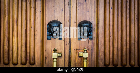 Détail de deux têtes de sphinx en bronze sur une vieille porte en bois - autour de 100 ans, palais italien dans le nord de l'italie Banque D'Images