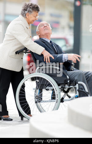 Senior man in wheelchair poussés par des femme Banque D'Images