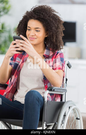 Femme handicapée dans un fauteuil roulant sur le téléphone Banque D'Images